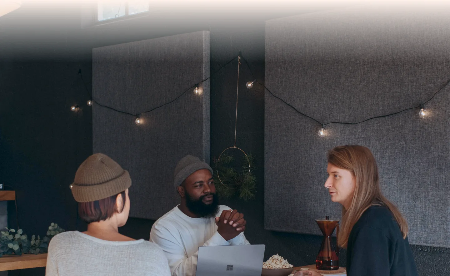 Three people talking around a table at a dim gathering