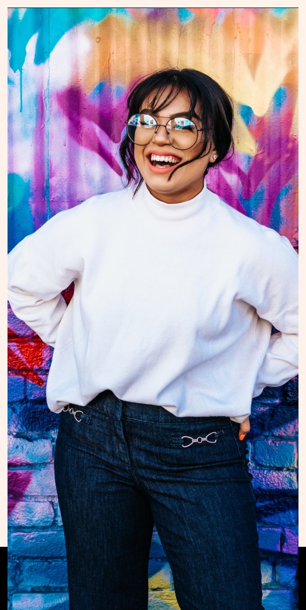 A laughing woman in front of a colorful mural